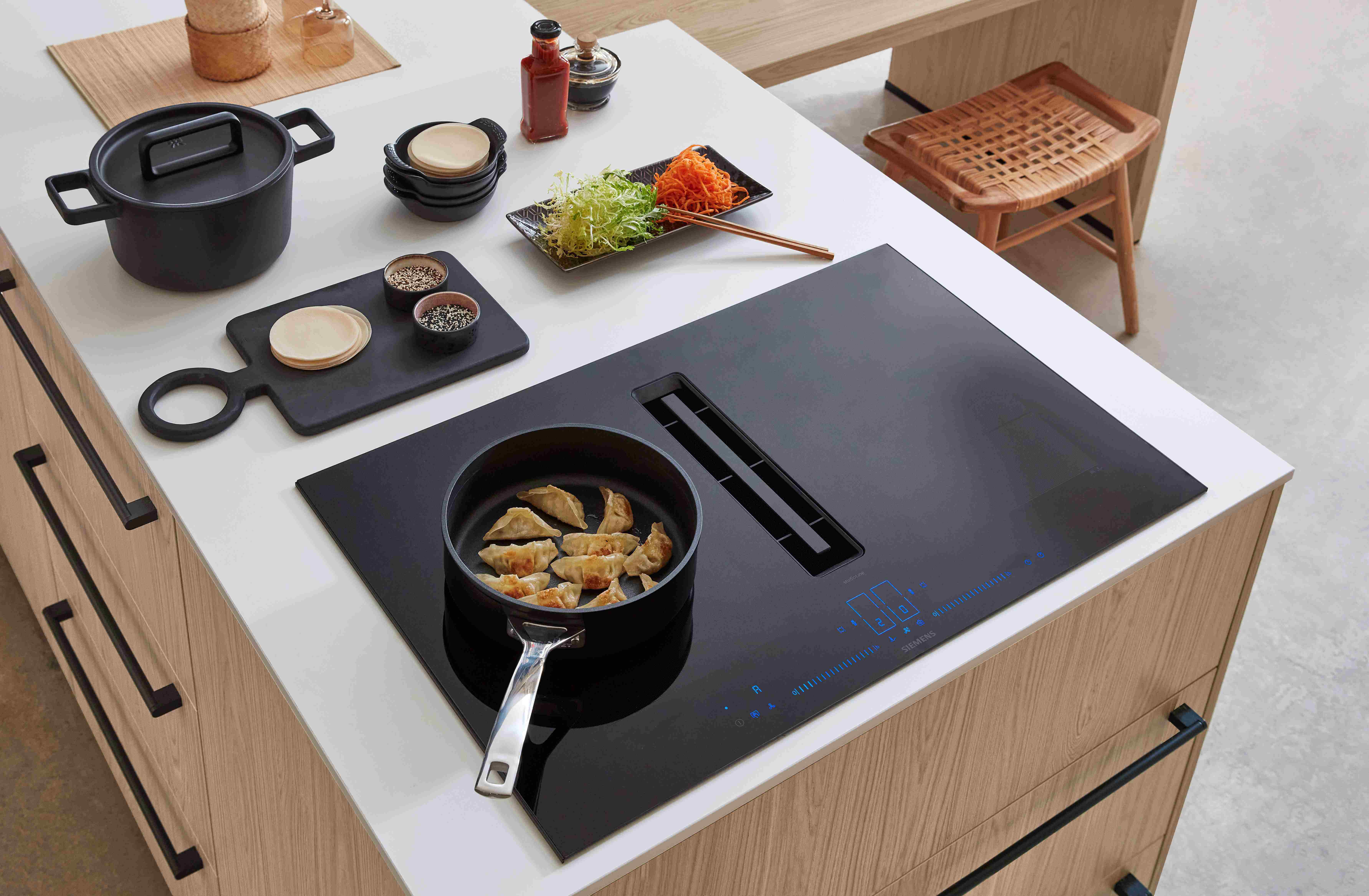 Induktionskochfeld von Siemens auf einer Kücheninsel, Matt weiße Inseloberfläche und Eichenfronten