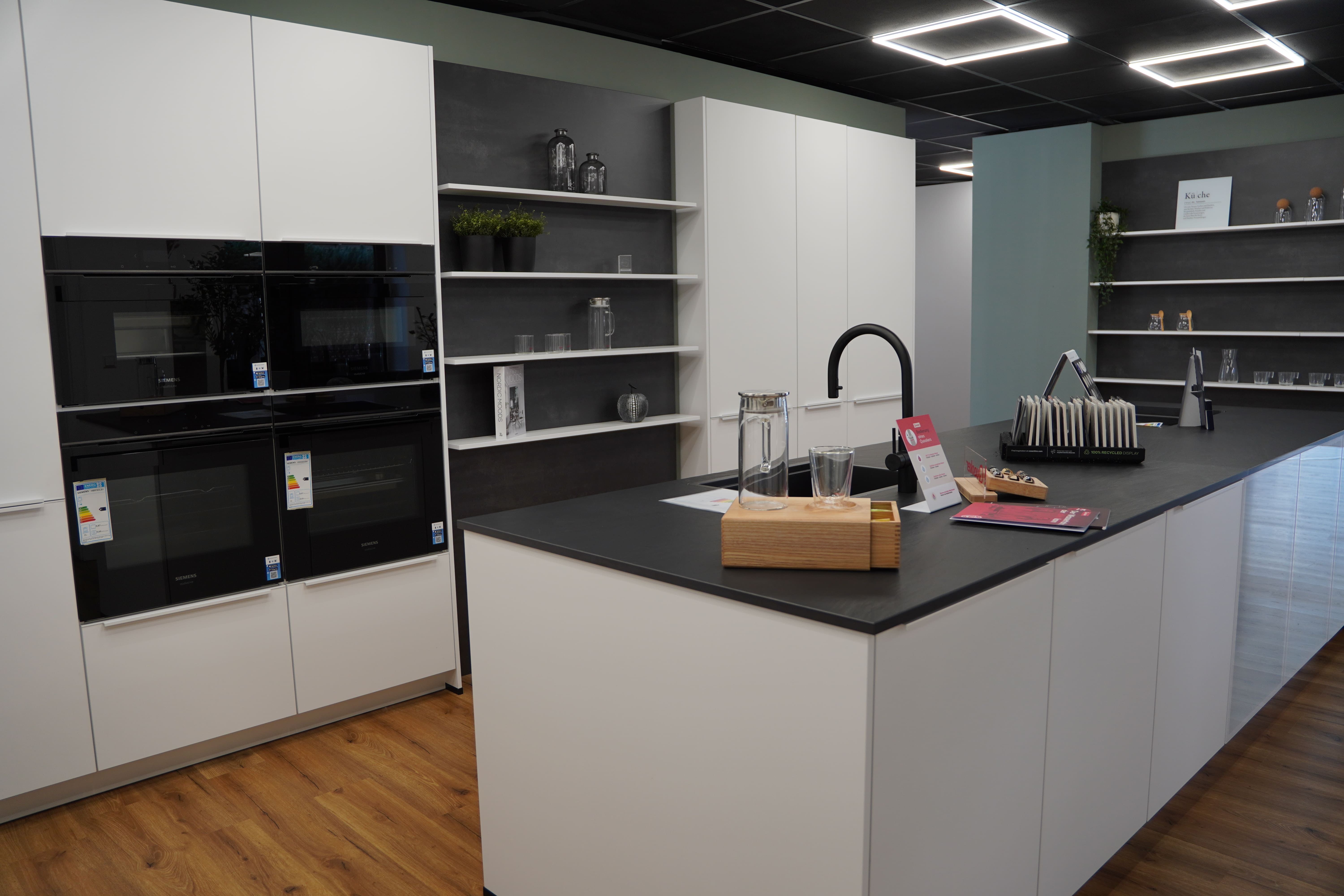 weiße Küche mit dunkler Arbeitsplatte und Kücheninsel